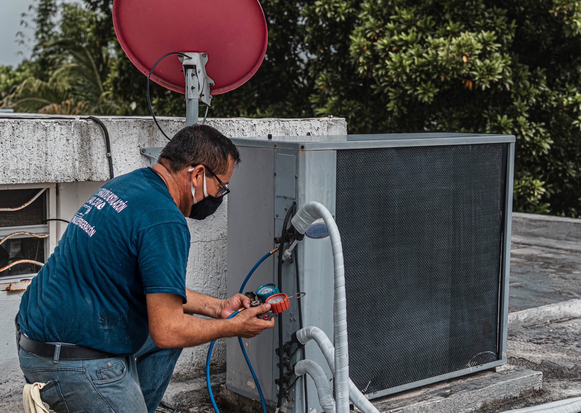 A technician servicing a home air conditioner with manifold gauges
