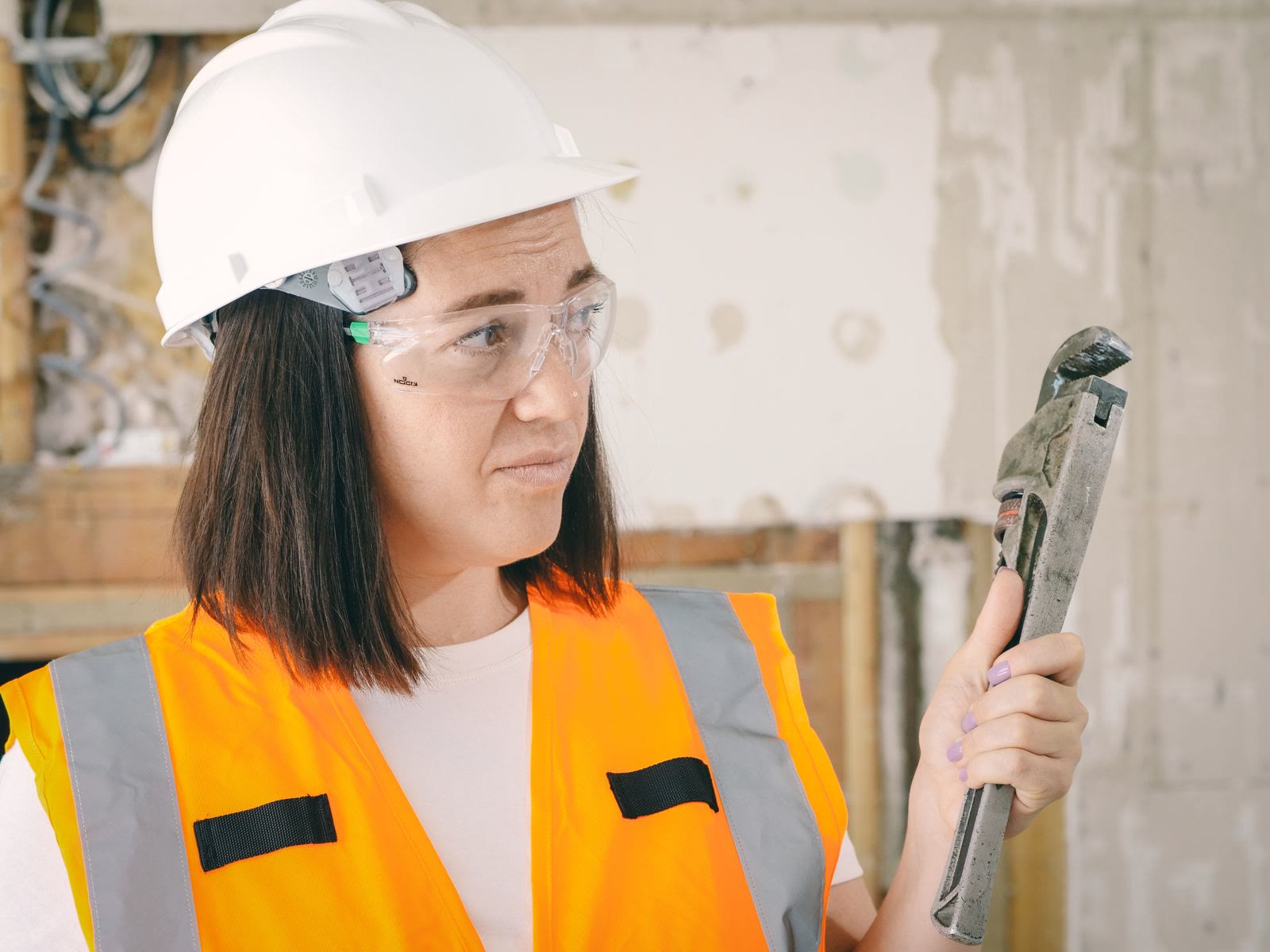 A plumber holding a pipe wrench inside a home